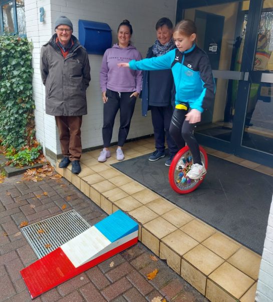 Jens Lemke aus aus der Gruppe „LEGO Rampen Aktiv“, Sportland-Leiterin Johanna Kreker und Inklusionsbeauftragte Uta Herrnring-Vollmer (von links) schauen gespannt, als die zwölfjährige Charlize Rothwell den bisherigen Teil der Rampe testet