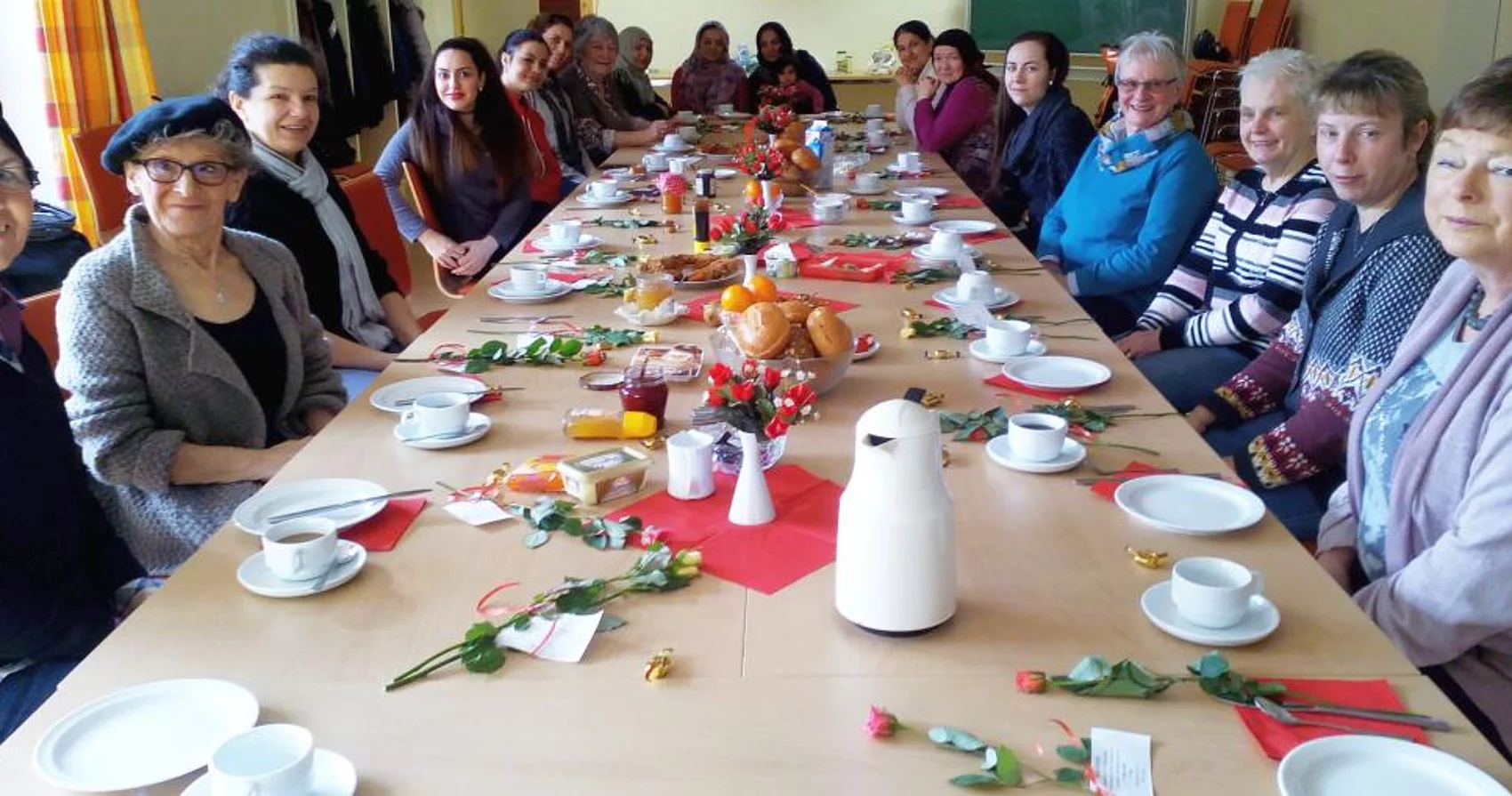 Frauen mit internationaler Herkunft sitzen gemeinsam an einem Frühstückstisch