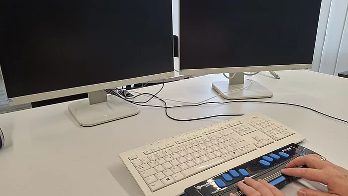 Schreibtischarbeitsplatz mit Monitor, Tastatur und zusätzlicher Braille-Zeile