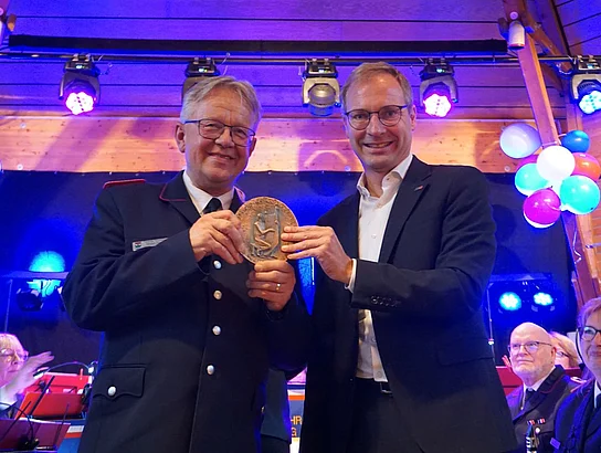 Zwei Männer halten eine Plakette hoch.