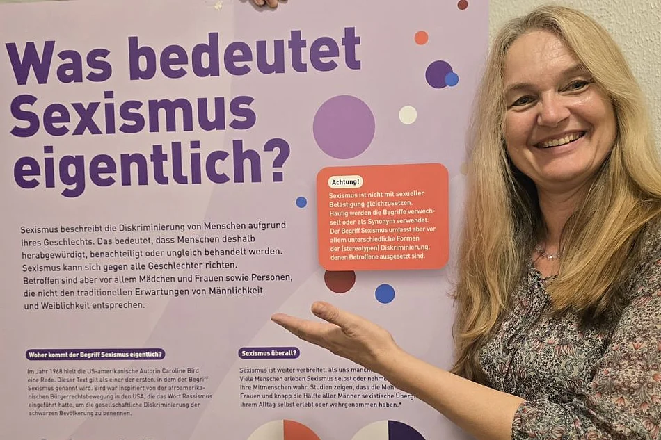 Eine Frau deutet auf ein Ausstellungsplakat.