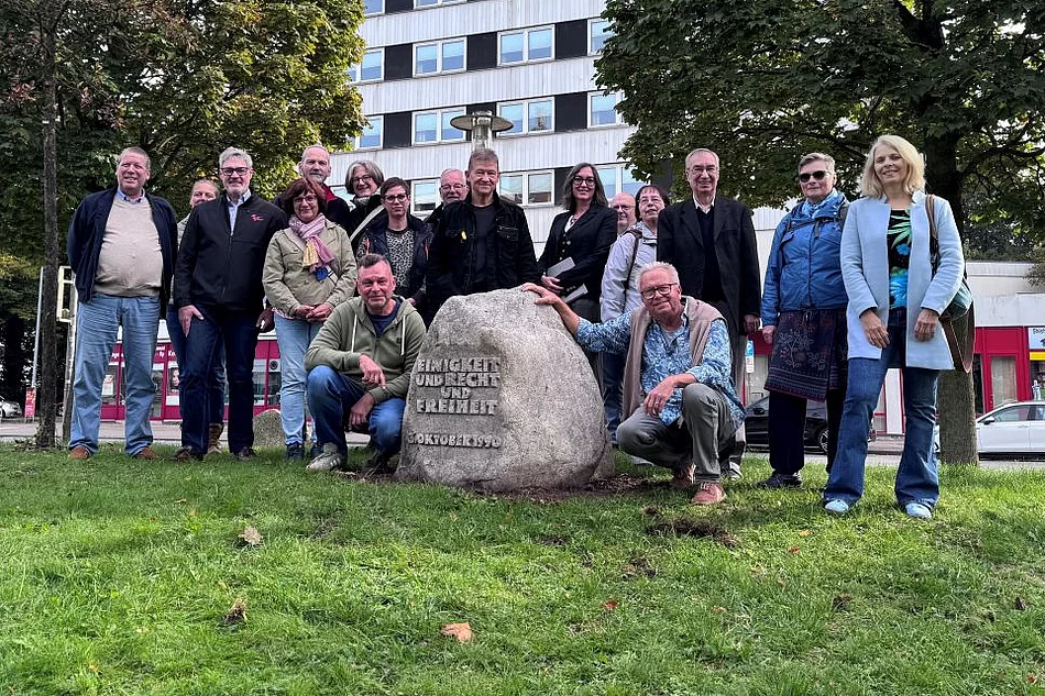 Mehrere Personen stehen um den Einheitsstein