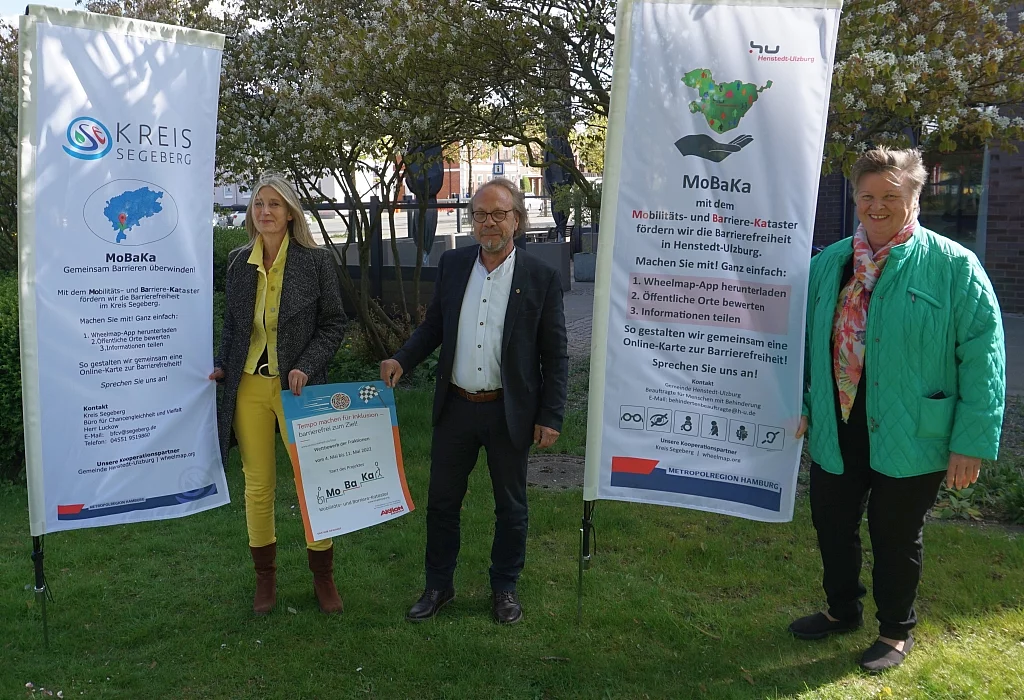 Die Inklusionsbeauftragten der Gemeinde sowie der Inklusionsbeauftragte des Kreises präsentieren Fahnen und Plakate des Mobilitäts- und Barriere-Katasters.