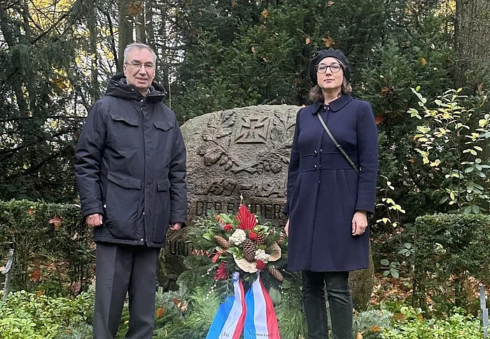 Zwei Personen stehen neben einem Kranz vor dem Ehrenmal.