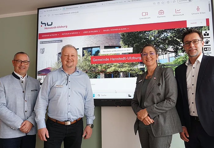 Vier Personen vor einem Bildschirm mit der Startseite der neuen Homepage.