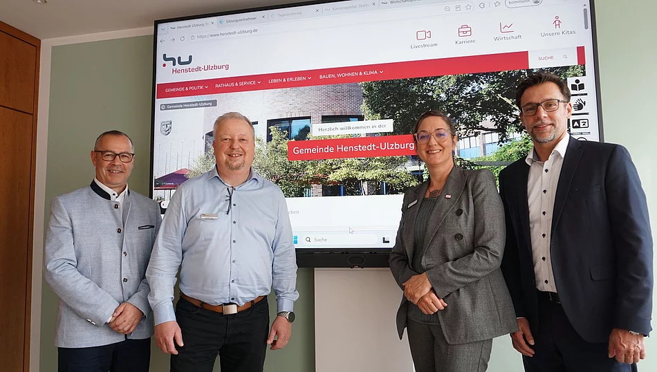 Vier Personen vor einem Bildschirm mit der Startseite der neuen Homepage.