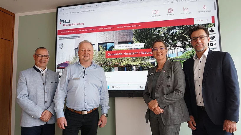 Vier Personen vor einem Bildschirm mit der Startseite der neuen Homepage.