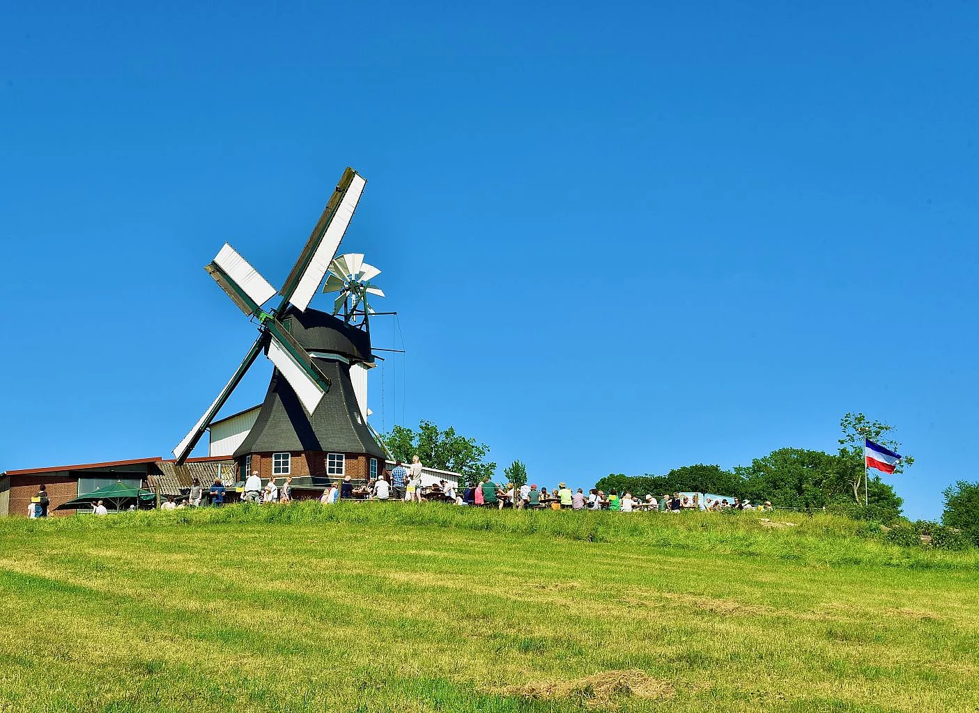 Blick auf die Ulzburger Windmühle mit Besuchern auf dem Mühlengelände