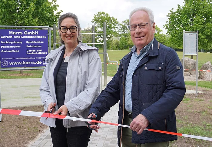 Zwei Personen stehen an der Calisthenic-Anlage vor einem Absperrband und halten Scheren in der Hand