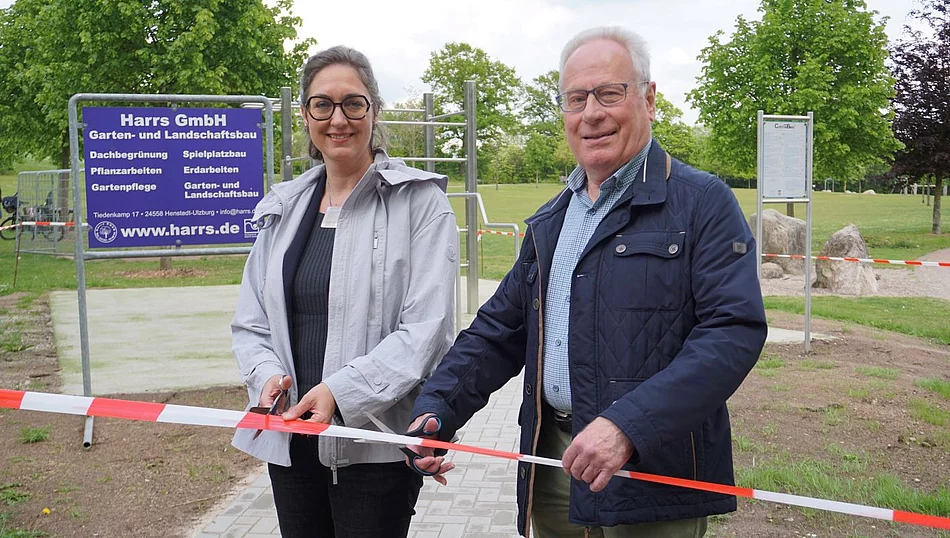 Zwei Personen stehen an der Calisthenic-Anlage vor einem Absperrband und halten Scheren in der Hand
