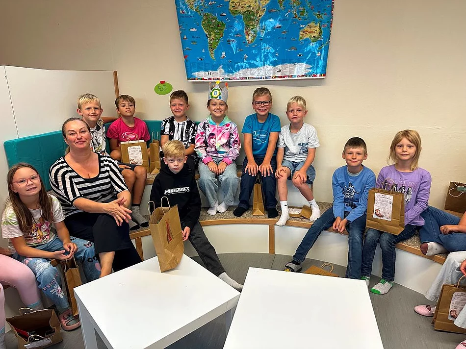 Bild mit einer Betreuungsperson und mehreren Kinder im einem Raum des Offenen Ganztags