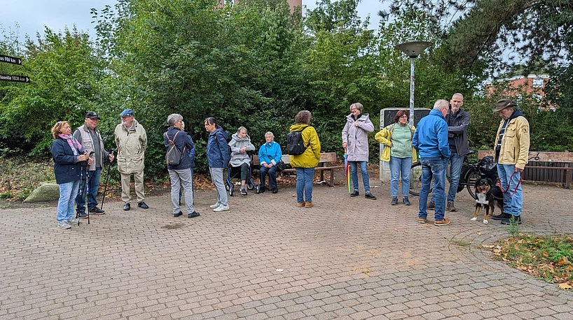 Mehrere Personen stehen am Treffpunkt für den Spaziergang. 