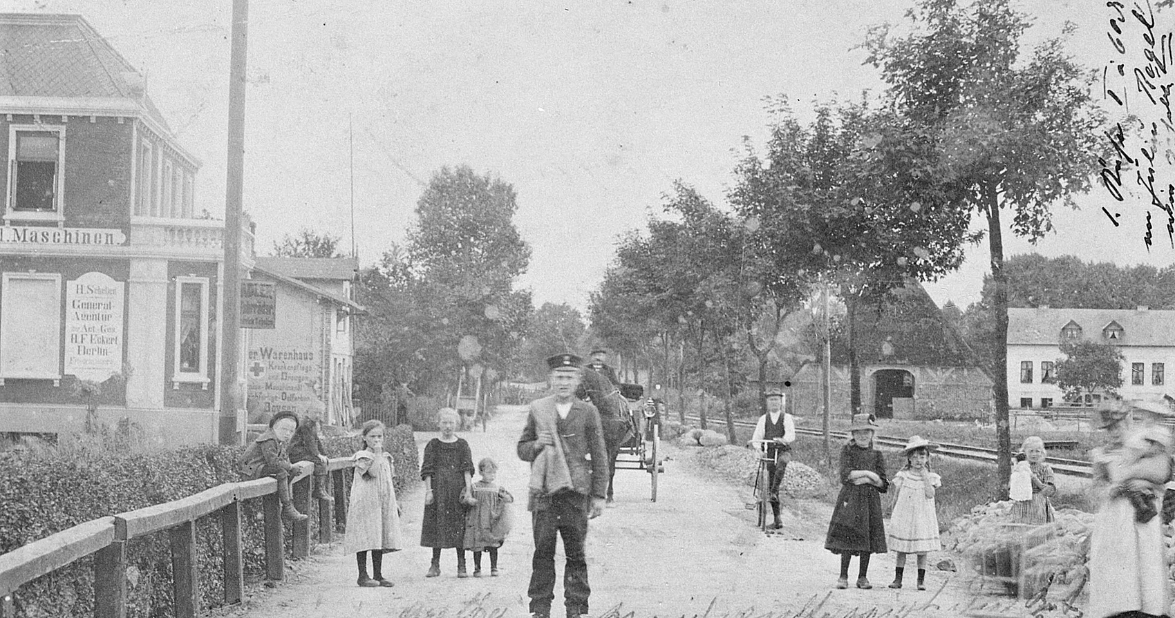Das Bild in Schwarz-Weiß zeigt die Hamburger Straße im Jahr 1902. Sie hat keinen Straßenbelag. Es sind mehrere Personen vom Kindes- bis zum Erwachsenenalter zu sehen, die auf der Straße stehen. Im Hintergrund steht auf der Fahrbahnmitte ein von einem Pferd gezogener Wagen, auf dem ein Mann sitzt. Rechts von der Straße verläuft eine Baumreihe und hinter dieser eine Bahntrasse. 